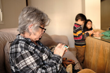 Grandmother distracted by her phone is taking care of her grandchildren at home