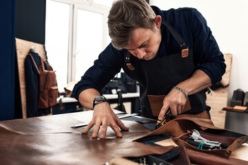 Skilled leather manufacture worker cutting some samples