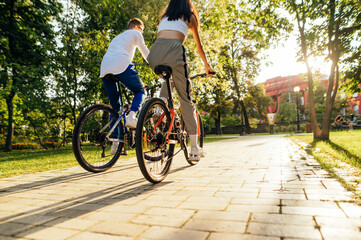 Two friends, a man and woman, are racing outdoors on their modern colorful bicycles. The couple is...