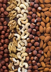 nuts of different types on a wooden table flat lay