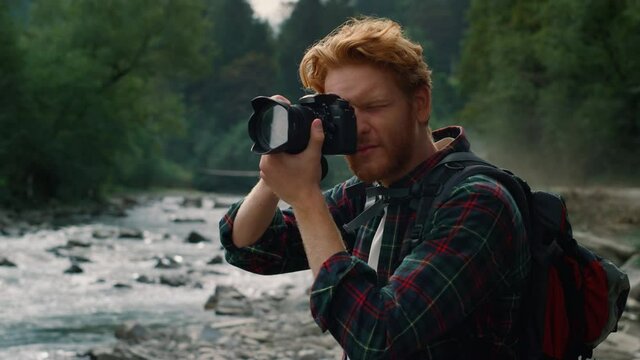 Guy taking photos on camera. Photographer adjusting zoom on camera lens