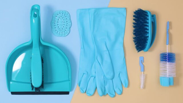 Blue cleaning household tools ordering on beige bright blue background. Stop motion flat lay