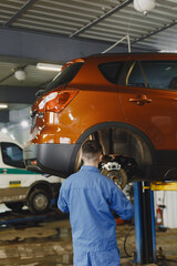 Man replaces wheel in car in garage on hoist