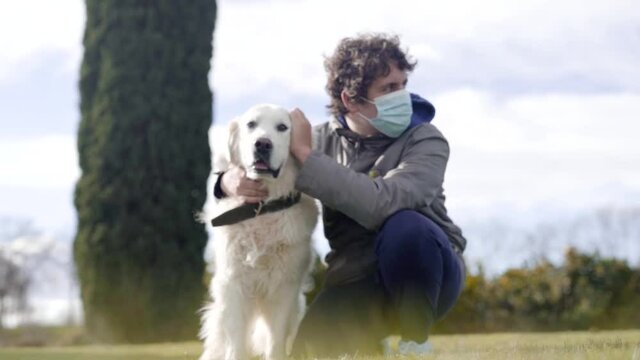 Young man caressing Golden retriever in nature park