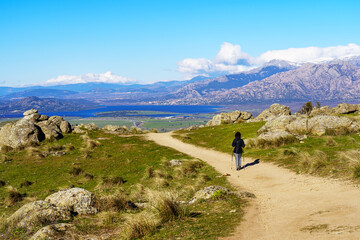 Fototapeta premium Woman hiking up the mountain paths to the top, with beautiful views of the landscape in the background.