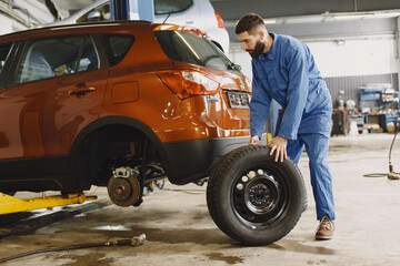 Man replaces wheel in car in garage on hoist