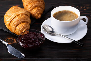 fresh croissants with jam and coffee on dark background. French breakfast