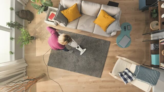 top down view of woman cleaning home using vacuum cleaner,young female doing housework in a modern apartment high angle view,housekeeping concept daylight shot
