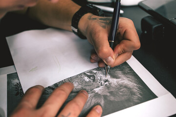 A tattoo artist sketching a tattoo in his tattoo studio.