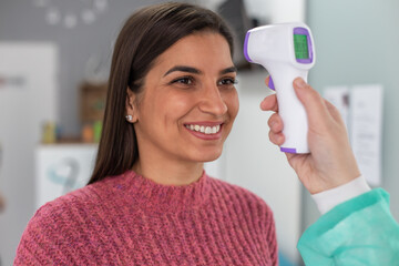 The doctor is measuring the woman's temperature using a thermometer. 