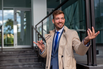 Portrait of a smiling businessman with glasses standing in the front of the building.