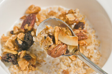 Fototapeta na wymiar top view, close up of a white bowl of granola with milk and a spoon full of granola to be eaten