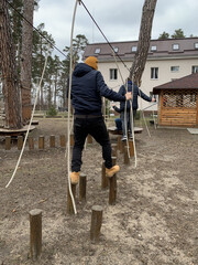 Men walk along the obstacle course. A park with an obstacle course for adults. Walking on stumps and ropes.