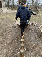 Men walk along the obstacle course. A park with an obstacle course for adults. Walking on stumps and ropes.