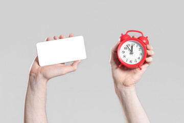 Mobile phone and alarm clock in hands on grey background. Mock up. Online buying and booking concept.