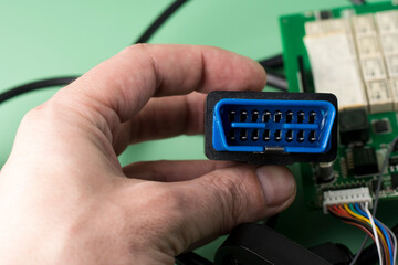 Electrician holds in hands car diagnostic error scanner OBD2 plug. Computer diagnostics of car engine device equipment, diagnostic interface. Service, repair, maintenance car concept.