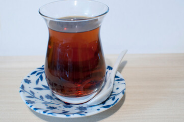 Black tea in a glass Turkish glass on a saucer on a light background. Background, texture.