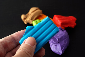 A man holding a piece of polymer clay in his hand. Low key. Close up.