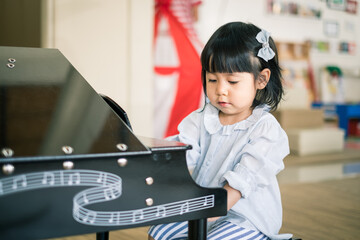 a toddler girl is playing mini piano.