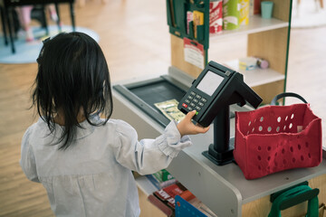 A Toddler plays shopping and touch cashier to make a payment.