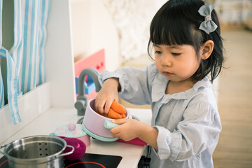 A toddler girl is playing kitchen toy.