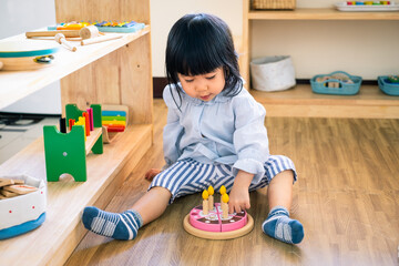 A toddler girl is playing a wooden toy cake. - 424819413