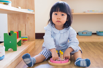 A toddler girl is playing a wooden toy cake. - 424819435