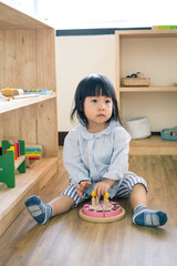 A toddler girl is playing a wooden toy cake. - 424819445
