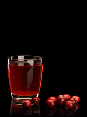 Glass filled with cranberry berry juice and scattering of berries of cranberry