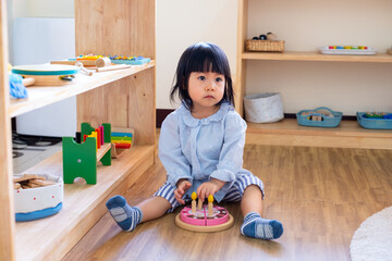 A toddler girl is playing a wooden toy cake. - 424819474