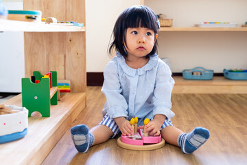 A toddler girl is playing a wooden toy cake. - 424819487