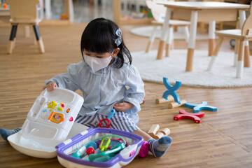 A toddler girl wear mask playing toy.