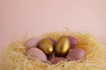 Easter eggs in a nest of straw on a gentle pink background