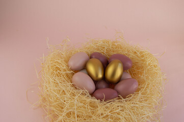 Easter eggs in a nest of straw on a gentle pink background