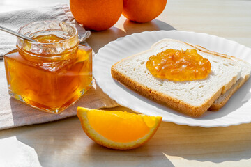 Slices of bread toast with homemade orange jam for breakfast on a wooden background. Breakfast concept
