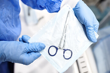 Sterilizing medical instruments in autoclave. Close up dentist assistant's hands holding packaged...