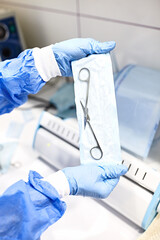 Sterilizing medical instruments in autoclave. Close up dentist assistant's hands holding packaged...