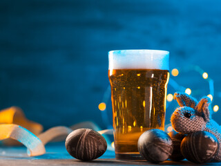 A glass of light beer for the Easter holiday, Easter unusually colored stone eggs, knitted bunny, copy space blue light background