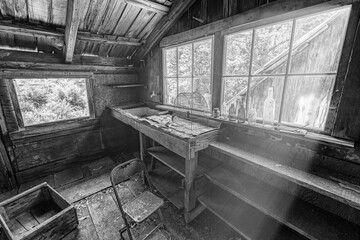 Black and white image of the interior of an abandoned cabin. - 424822839