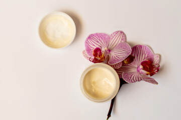 Bowl of cream on white with orcgids, top view. image of homemade cosmetics ingredients. aroma theme. organic cosmetics.