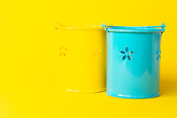 decorative yellow and blue buckets on a yellow background. Farming or repair concept. Small Buckets for planting flowers
