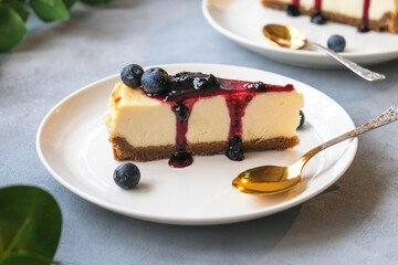 Portion of cheesecake poured blueberry jam decorated fresh blueberries. Delicious cheese pie on plate. 