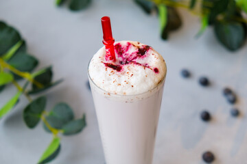 Glass of milkshake with blueberries sprinkled with chocolate chips.