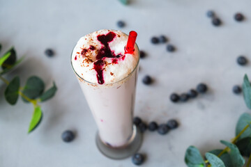 Glass of blended milk cocktail with blueberries sprinkled with chocolate chips.