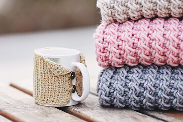 Stack of colorful knitted scarfs and cup. Autumn mood.  Hot cup of coffee. Warm clothes. Selective focus 