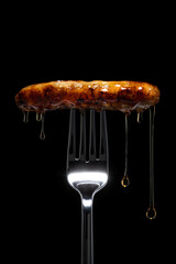 Breakfast sausage dripping with syrup on a fork