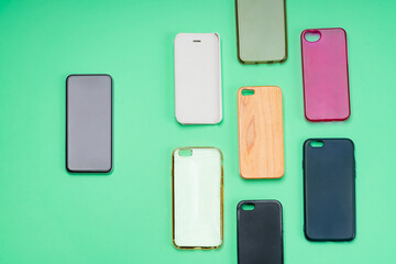 Choice of multicolored plastic back covers for mobile phones on green background with a smart phone on the side