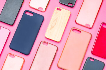 Pile of multicolored plastic back covers for mobile phone. Choice of smart phone protector accessories on pink background. A lot of silicone phone backs or skins next to each other