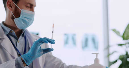 Young doctor spraying antibacterial liquid wiping hands in gloves doing vaccine injection for...