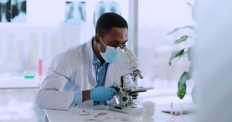 Afro-americcan young biologist doctor examining bacteria in medical office laboratory taking...